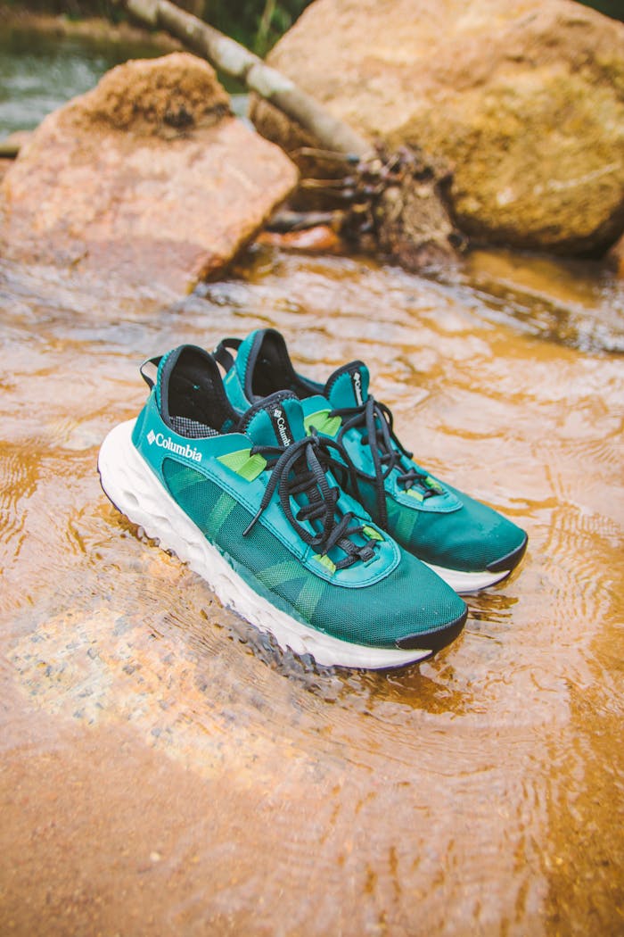 Green sneakers resting in a creek bed in Đà Lạt, Vietnam, highlighting outdoor adventure lifestyle.